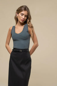 Woman in blue-gray scallop edge sleeveless sweater knit crop top and black skirt