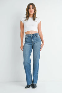 Woman in blue jeans and white crop top showcasing longer length straight denim jeans