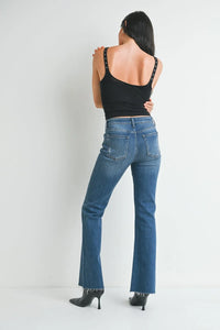 Woman in medium rise waist flare denim jeans and a black top, viewed from behind