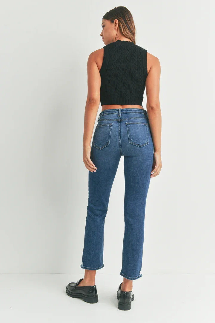 Woman in distress denim slim straight jeans and black crop top viewed from behind