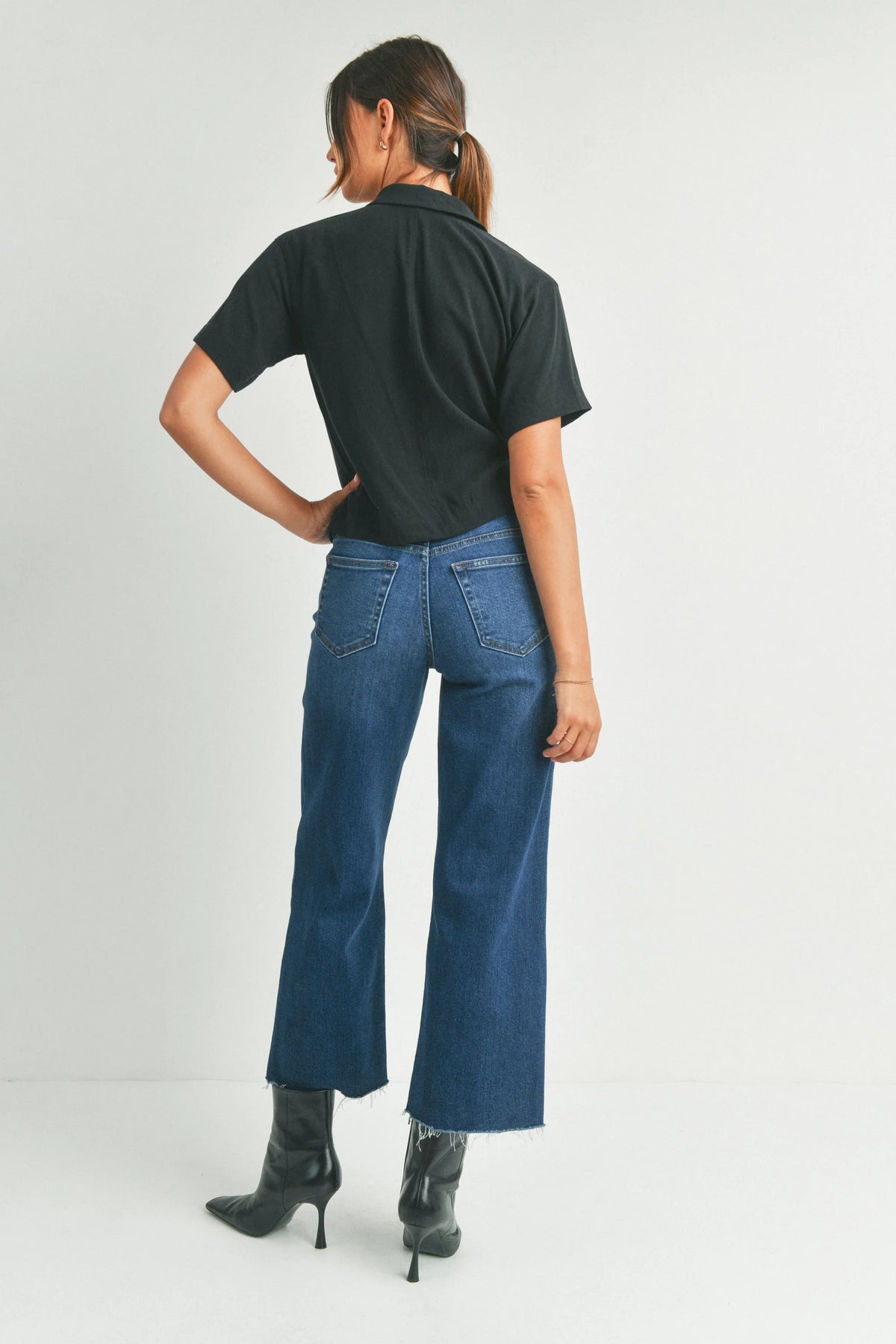 Woman with a free spirit in blue jeans and black t-shirt showcasing Slim Wide Leg Denim