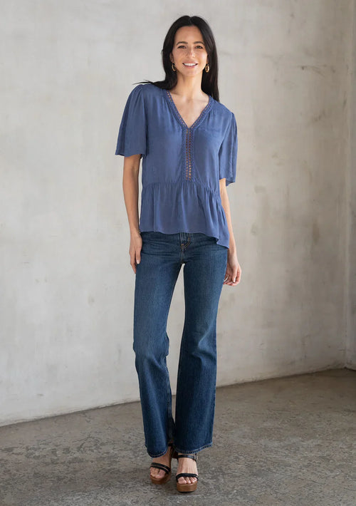 Woman wearing floral jacquard airy short sleeve peplum blouse with blue peplum top and jeans