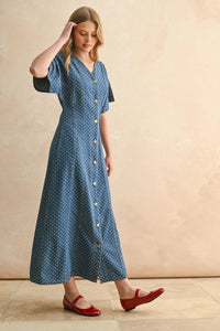 Woman modeling a blue dot print midi dress with short sleeves and red Mary Jane flats for women’s boho chic clothing at Shop Daisy