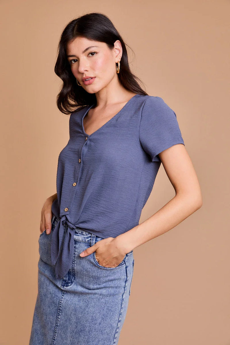 Woman modeling a short sleeve, flowy boho top with jeans in blue hue