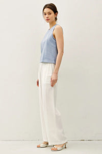 Woman wearing a blue acid wash boxy cut tank top and white pants