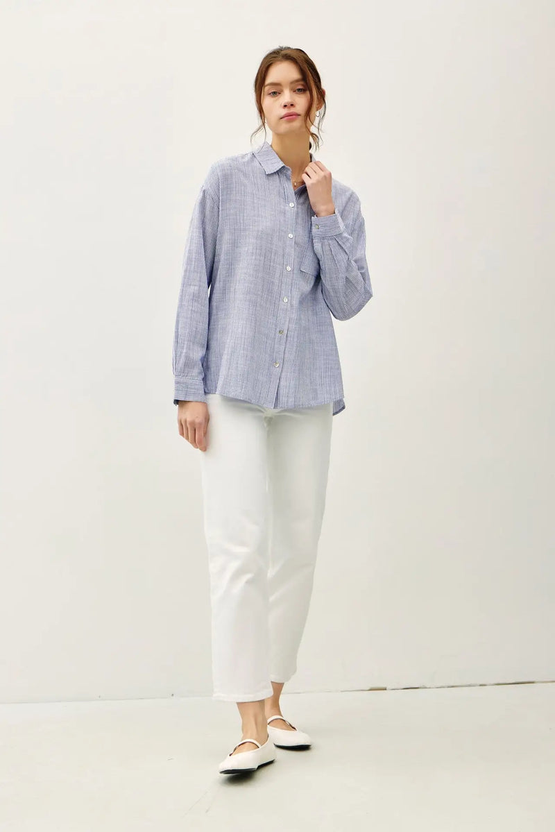 Woman in a blue striped PINSTRIPE BUTTON DOWN SHIRT, perfect for women’s boho chic clothing at Shop Daisy