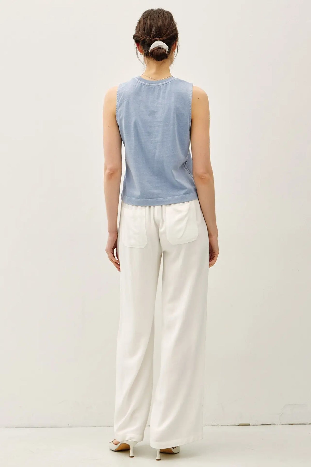 Woman in a blue tank top and white pants wearing the acid wash boxy cut tank