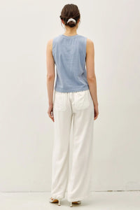 Woman in a blue tank top and white pants wearing the acid wash boxy cut tank
