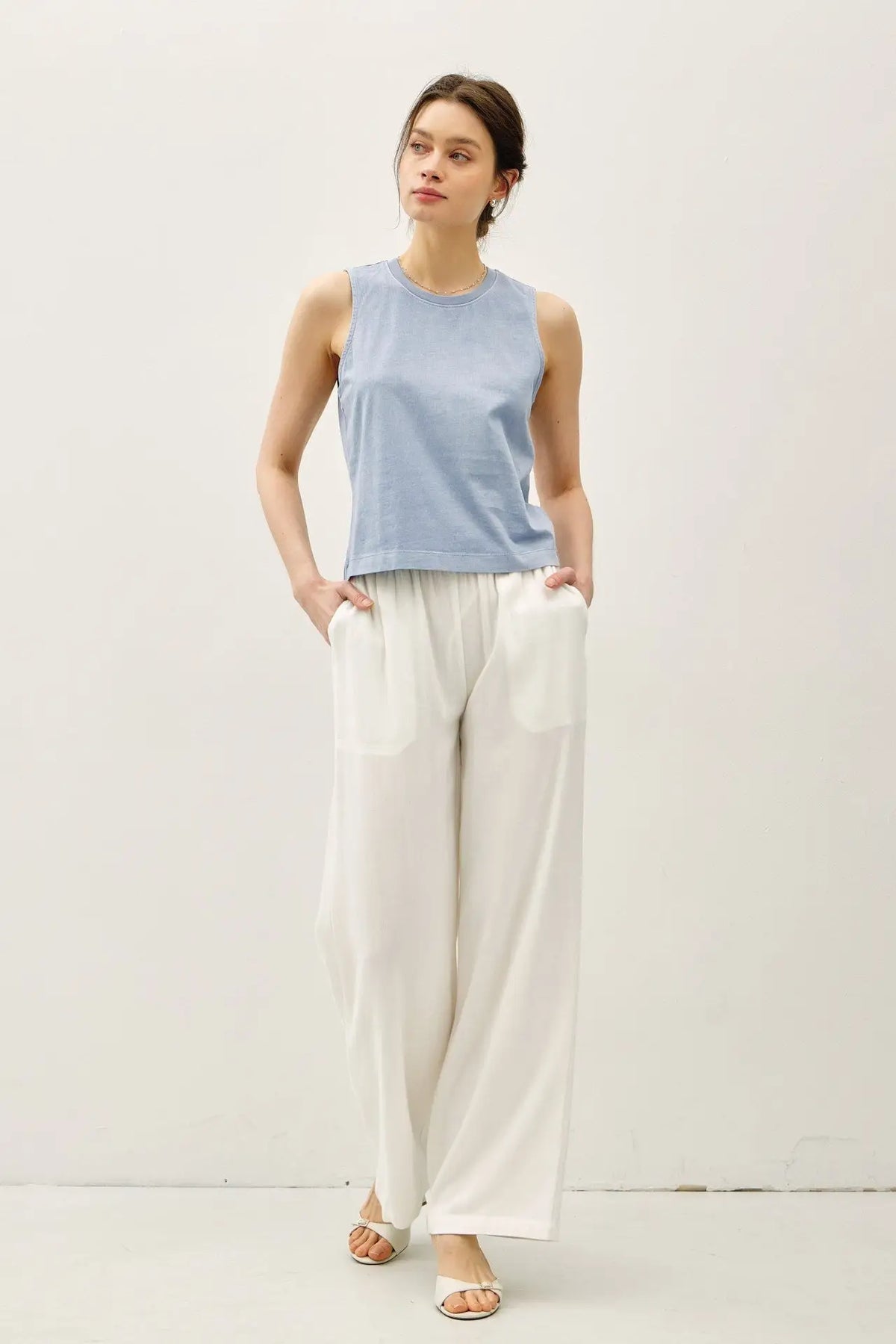 Woman wearing a blue top and white pants in the BASIC CROPPED ACID WASH BOXY CUT TANK