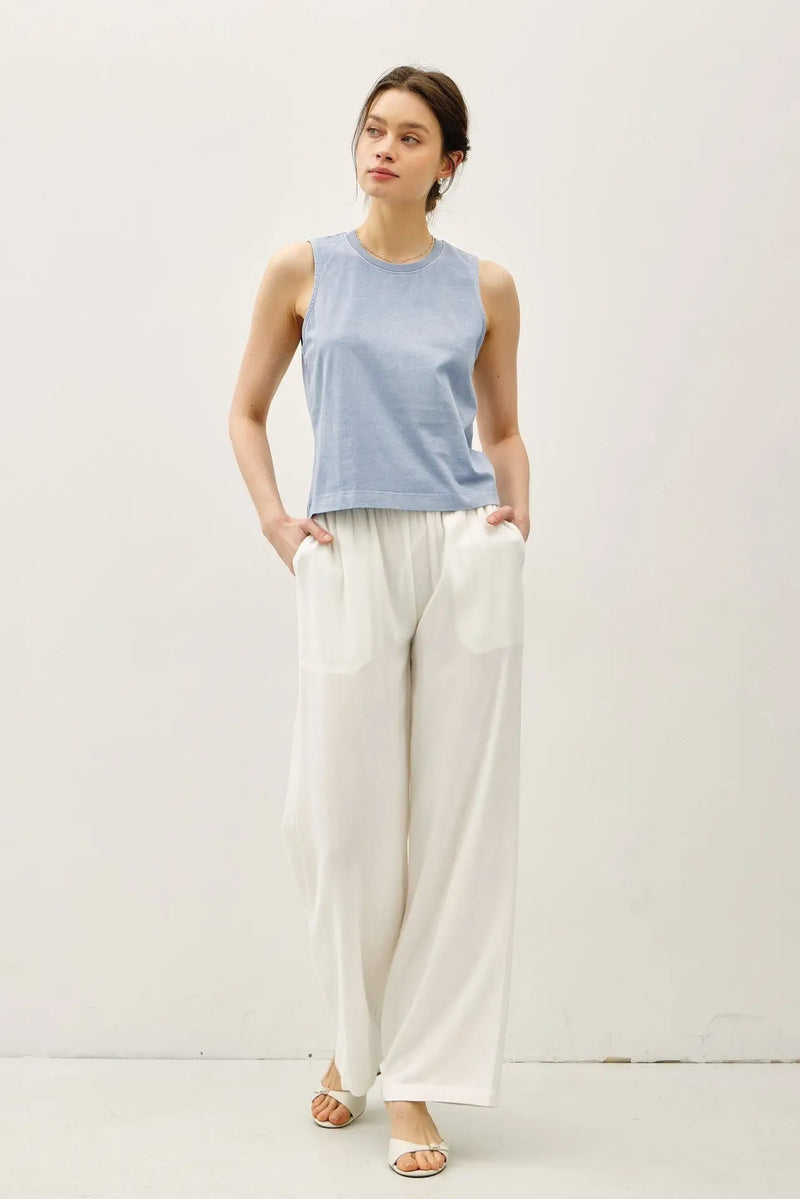 Woman wearing a blue top and white pants in the BASIC CROPPED ACID WASH BOXY CUT TANK