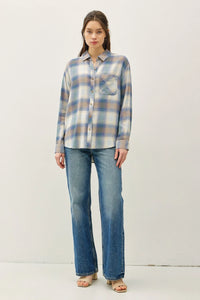 Woman wearing a vintage plaid boxy shirt in blue and white plaid with blue jeans