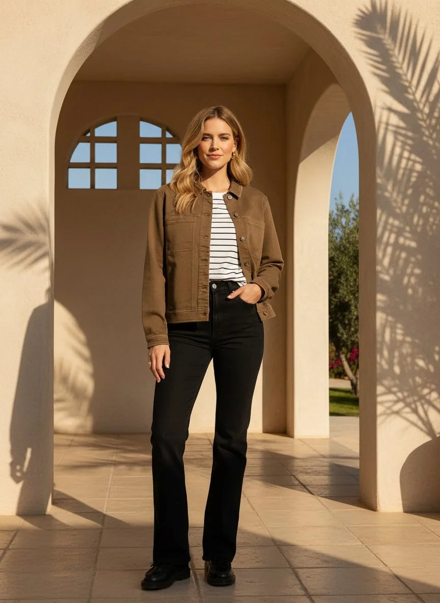 Woman wearing a brown supply Siena jacket, striped t-shirt, and black jeans