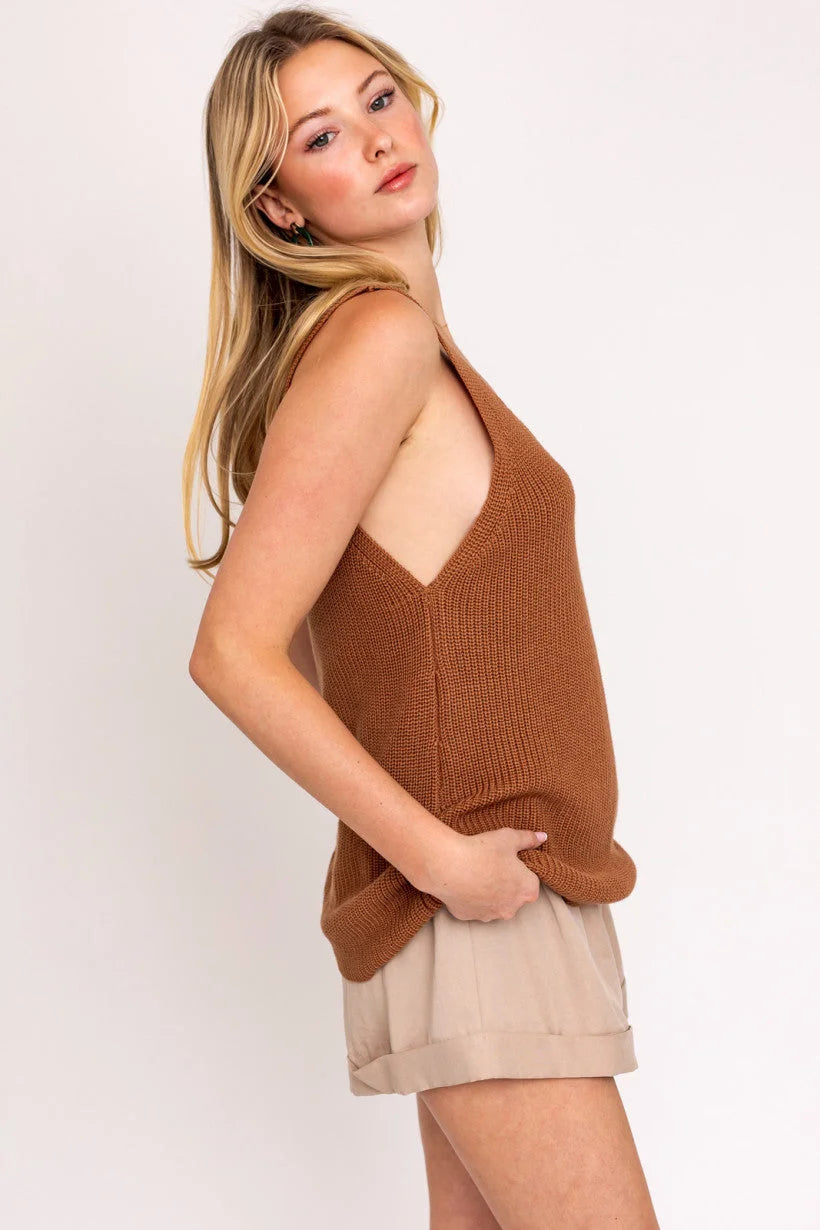 Woman in a brown knit deep v neck tank top and beige shorts showcasing boho style