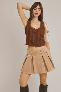 Woman in brown scoop neckline summer top with trim detail and pleated skirt