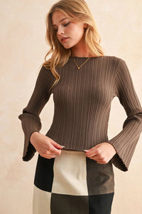 Woman modeling a ribbed long sleeve knitted top with bell sleeves and patchwork skirt
