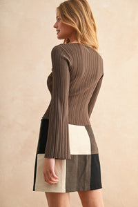 Woman wearing a ribbed long sleeve knitted top with a color-block mini skirt