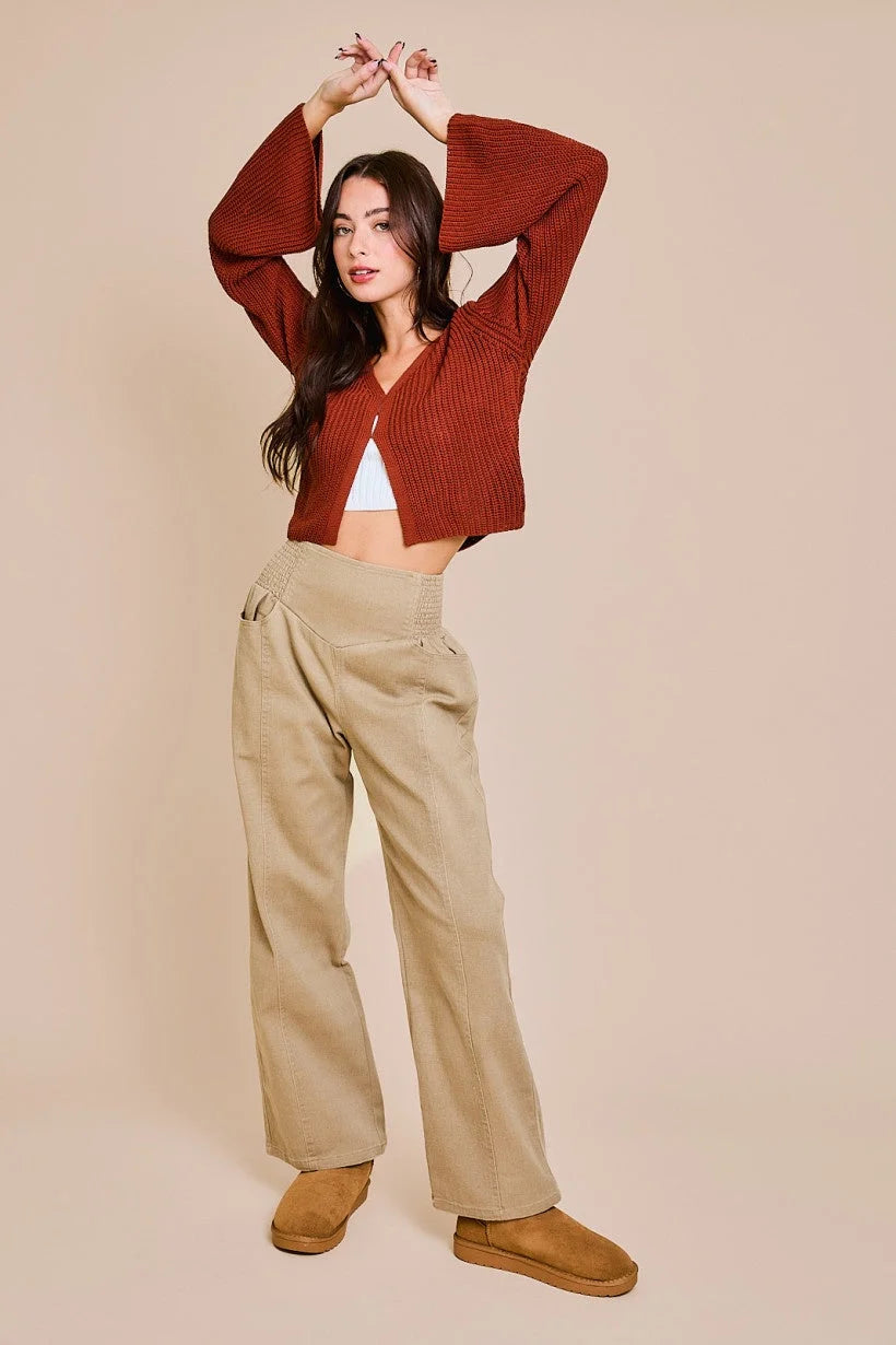 Woman in casual autumn outfit with rust bell sleeve cardigan and beige wide-leg pants