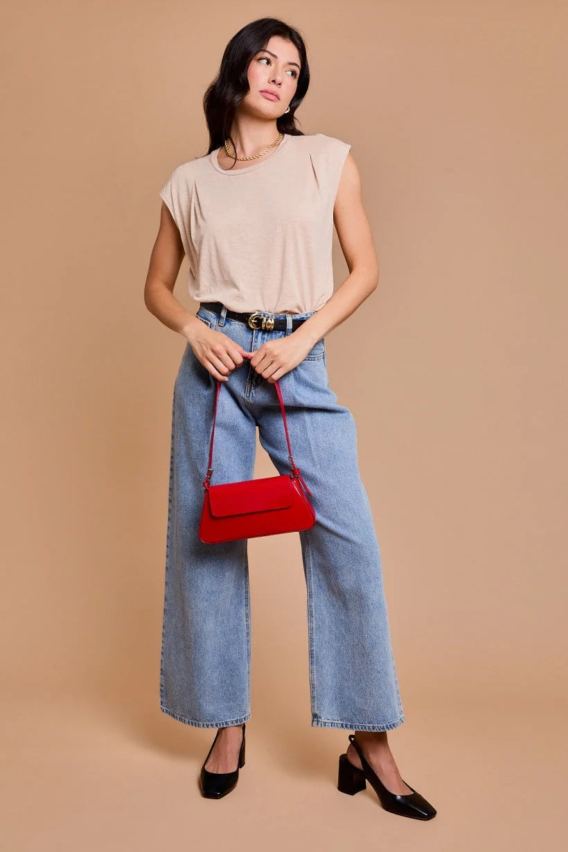 Woman in casual outfit showcasing pleated shoulder top and red handbag