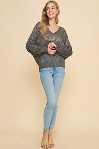 Woman in chunky gray open weave knit long sleeve sweater and light blue jeans