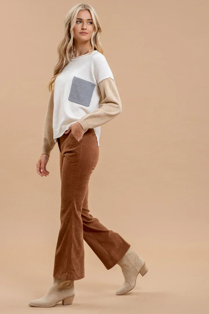 Woman in a colorblock long sleeve knit sweater paired with brown flared pants and beige boots