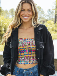 Smiling woman in colorful boho crop top and black jacket with Fuchsia Marigold headband