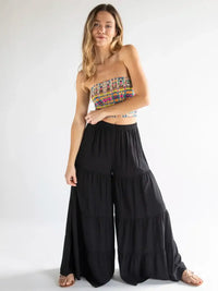 Woman in colorful strapless top and black palazzo pants embodies boho free spirit style