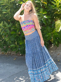 Smiling woman in colorful tube top and flowy blue skirt with Boho Rainbow Floral Rows headband