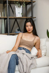 Woman relaxing on couch with blanket, showcasing seamless lace strap bralette features