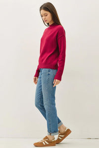 Woman wearing highneck basic cropped sweater, light wash jeans, and striped sneakers