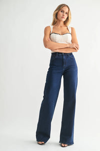Woman wearing high rise wide leg palazzo denim jeans with cream top and dark trim