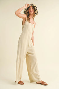 Woman in a cream-colored DYE & WASH JUMPSUIT with hair curlers, showcasing boho style