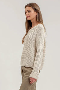 Woman in a cream chunky knit pullover sweater and beige pants for a boho look