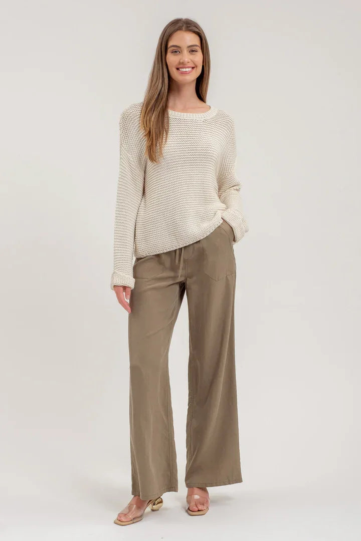 Woman in cream chunky knit pullover sweater and wide-leg khaki pants for a boho look