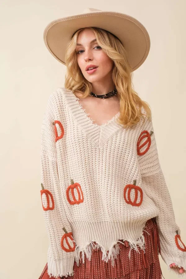 Woman in cream knit sweater with pumpkin design and hat, showcasing women’s boho chic clothing