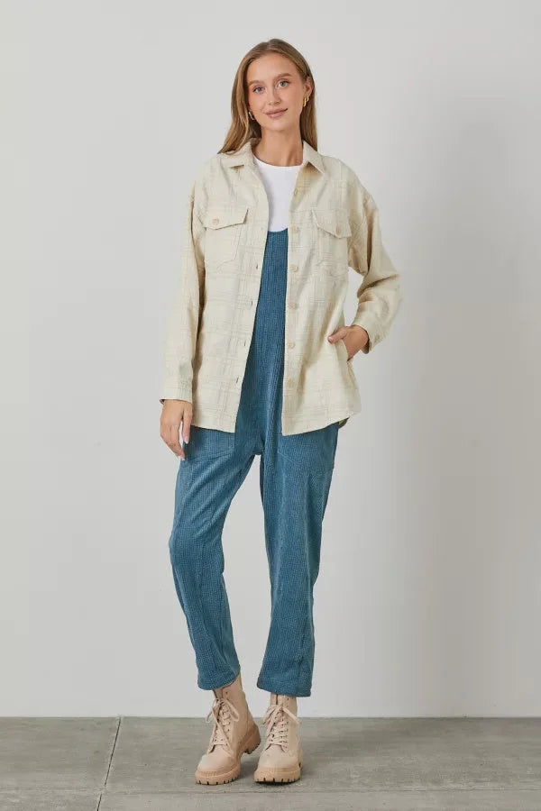 Woman styled in a cream plaid texture woven shacket, white tee, blue pants, and beige sneakers