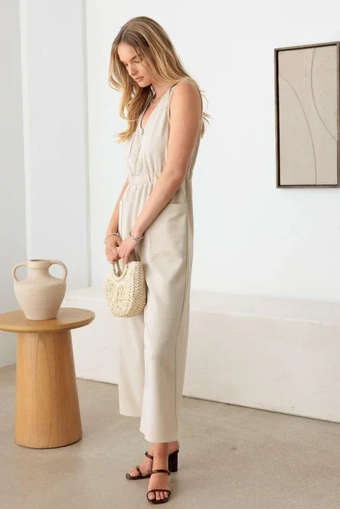 Woman in a cream sleeveless wide leg jumpsuit with a handbag for a boho look