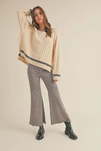 Woman in a cream sweater modeling plaid pattern flare pants for fashionable styling