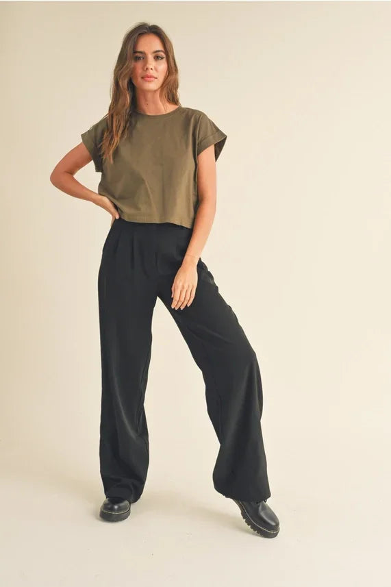 Woman wearing a round neck cuffed sleeve top in olive green with black wide-leg pants