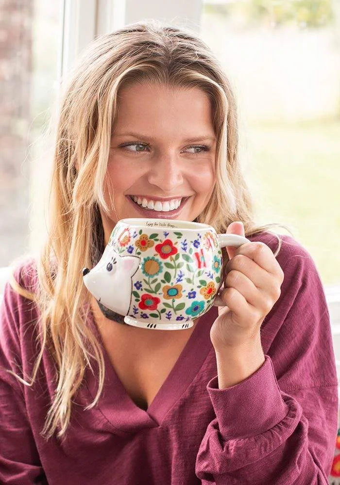 A woman holding a floral-patterned Hedgehog Folk Art Mug showcasing unique design