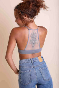 Woman with curly hair in blue denim top showcasing tattoo mesh racerback bralette