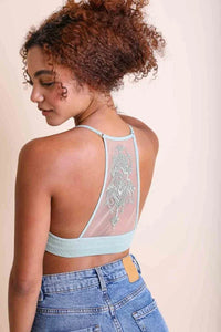 Woman with curly hair in a blue top showcasing a Tattoo Mesh Racerback Bralette