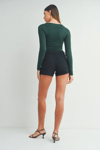 Woman in dark green long-sleeved top and black shorts showcasing Classic Clean Stretch Short