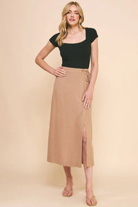 Woman models a flowy dark green crop top with a beige side slit midi skirt