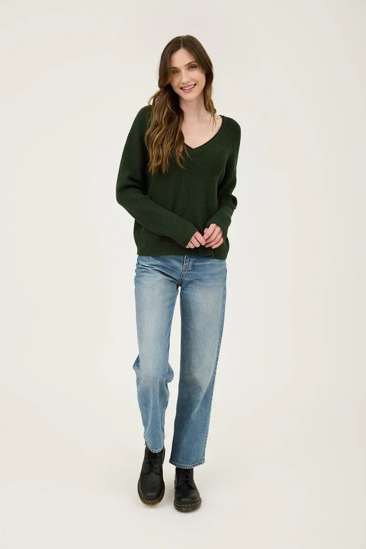 Woman wearing a dark green V Neck Long Sleeve Ribbed Sweater with blue jeans