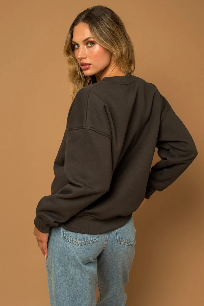 Woman in dark oversized long sleeve round neck fleece sweatshirt and light blue jeans