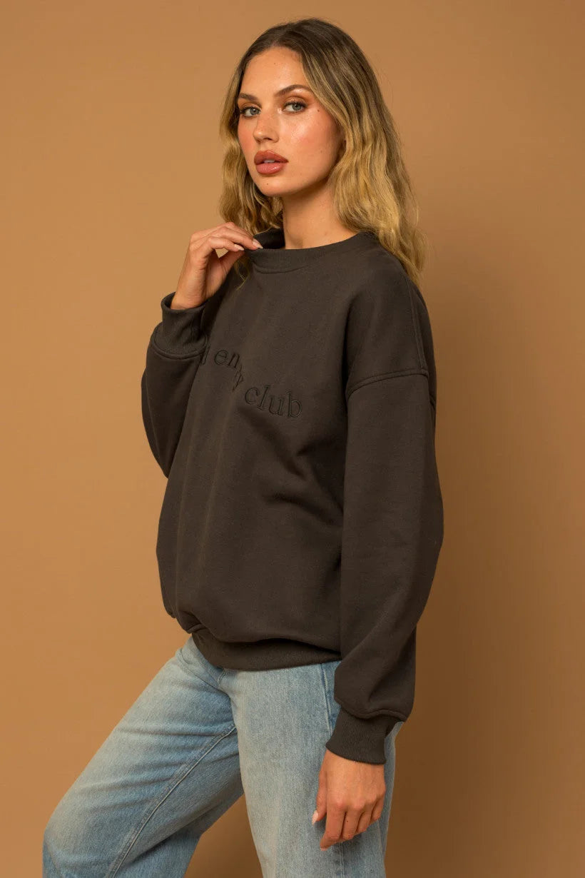 Woman in dark oversized round neck fleece sweatshirt with light blue jeans