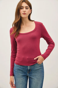 Woman wearing a dark red basic scoop neck long sleeve top and blue jeans