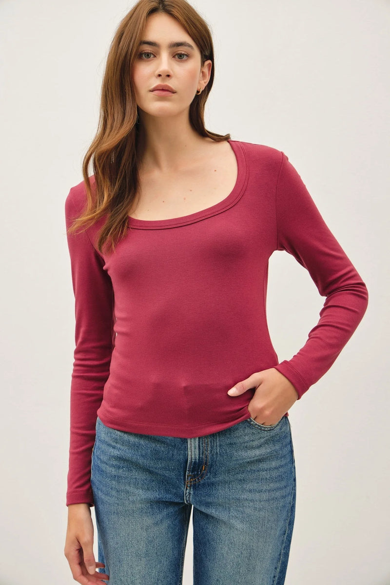 Woman wearing a dark red basic scoop neck long sleeve top and blue jeans