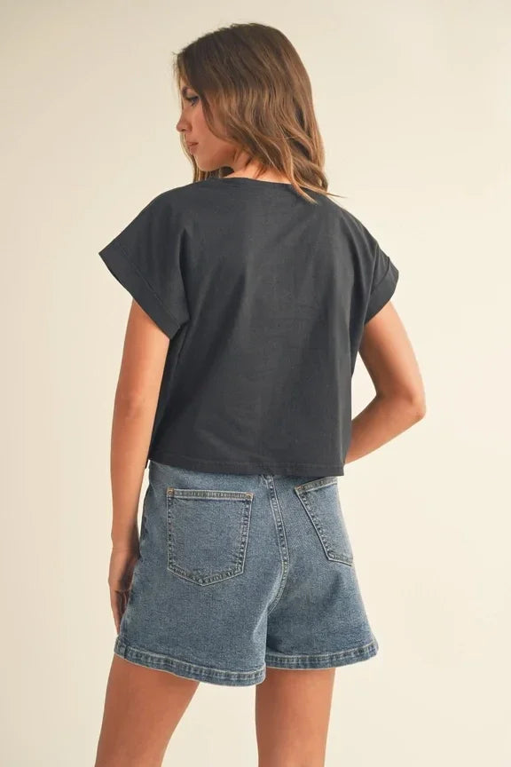 Woman in a round neck cuffed sleeve top and denim shorts, viewed from behind