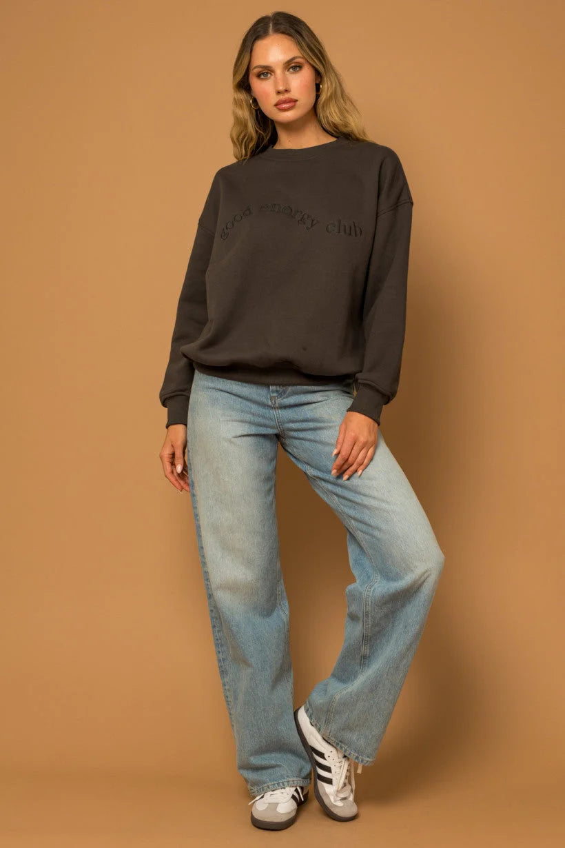 Woman in a dark sweater and light blue jeans wearing a Long Sleeve Round Neck Fleece sweatshirt